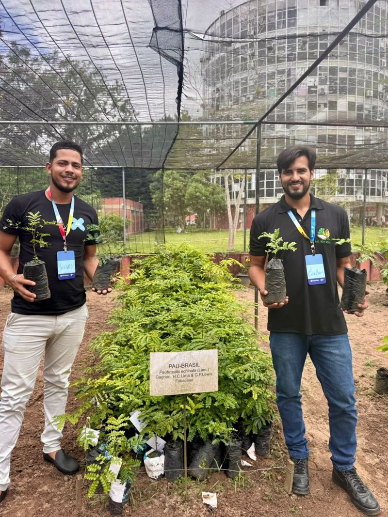 Dois sócios da EDUCACAU segurando mudas de pau-brasil em um viveiro